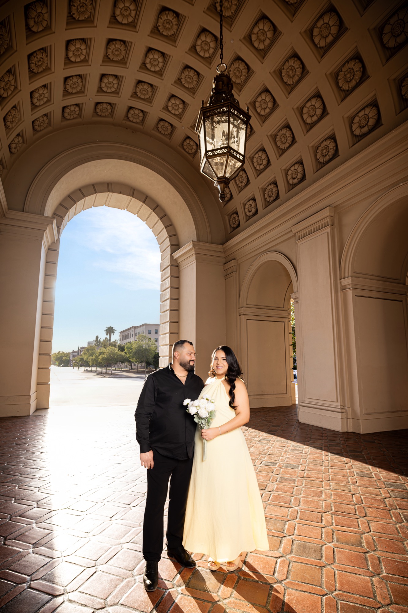 Couple standing beneath a grand architectural arch