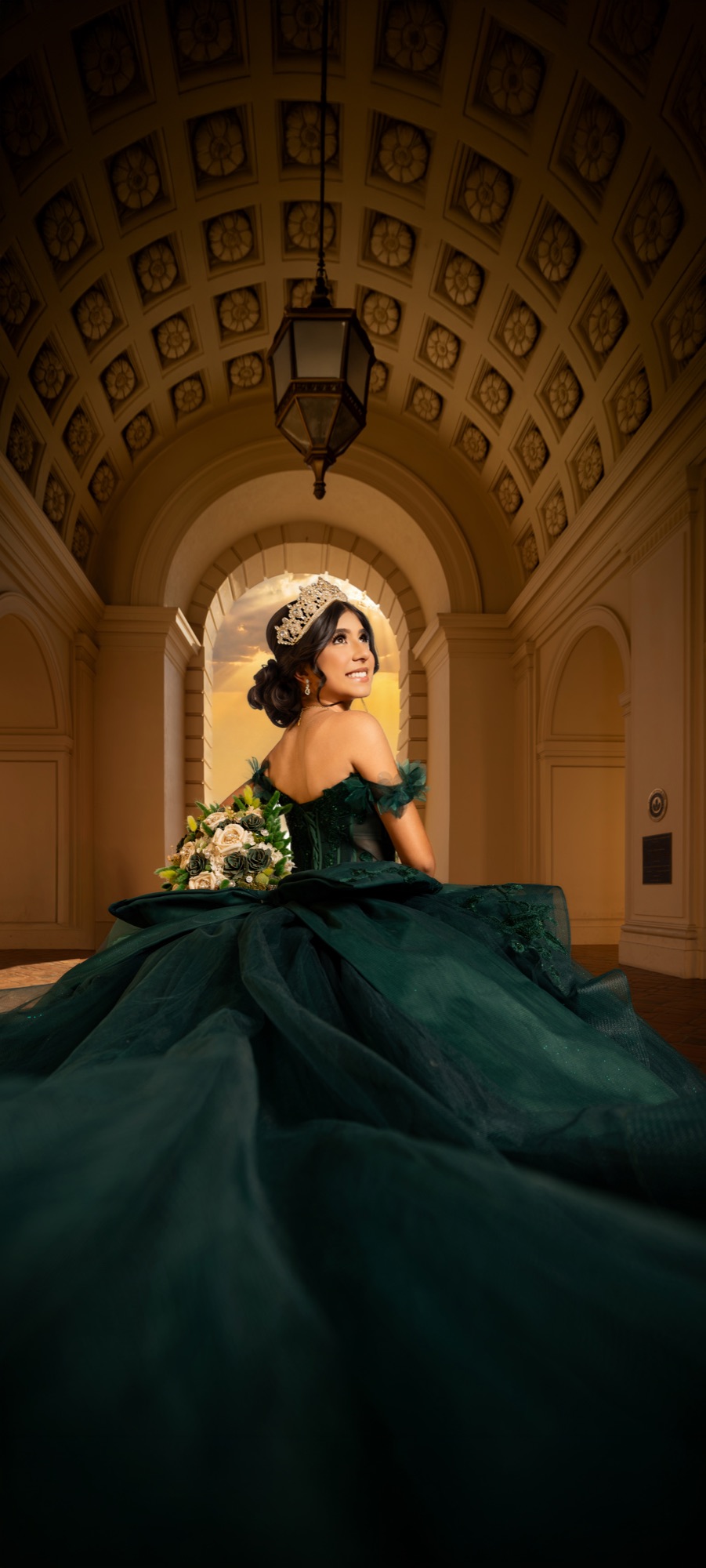 Emerald gown portrait under a warm architectural arch