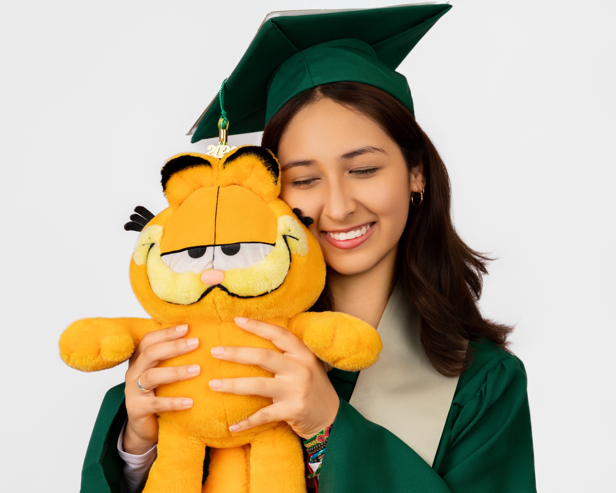 Graduate smiling while hugging a Garfield plush toy