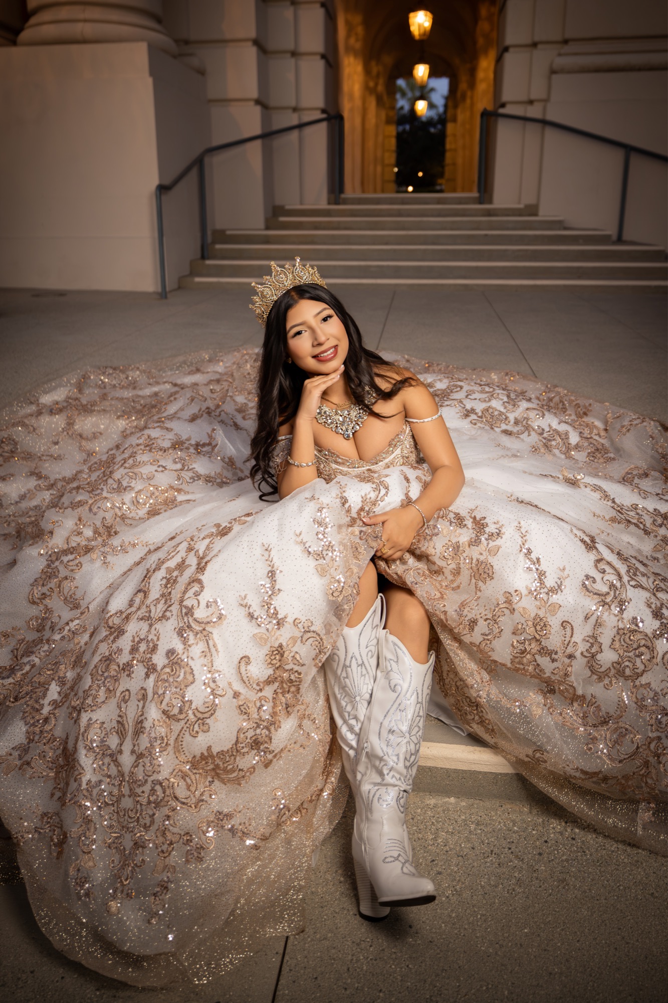 Quinceañera wearing a champagne gown and white boots on stone steps