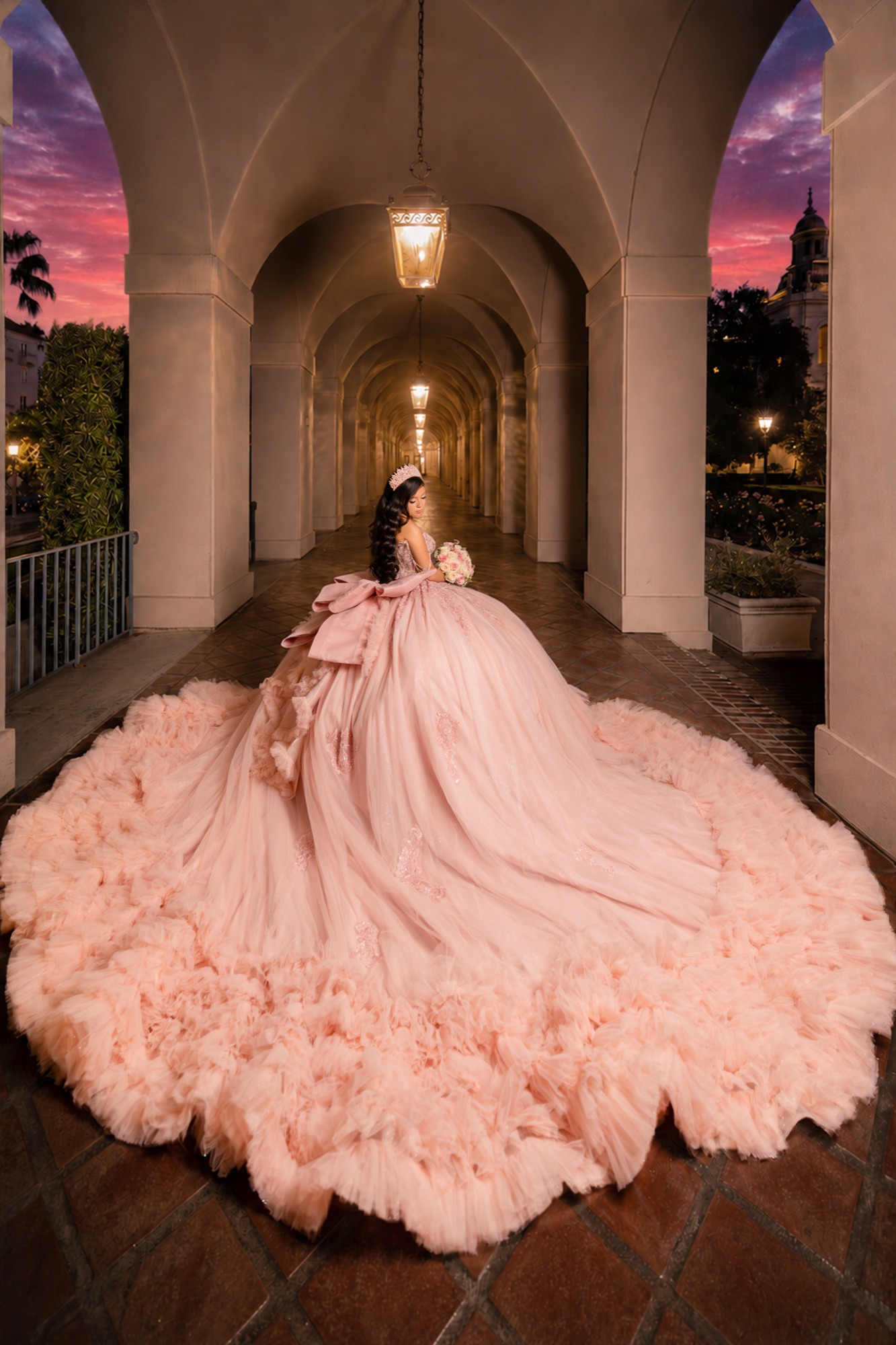 Pink gown with a sweeping train in an illuminated arcade